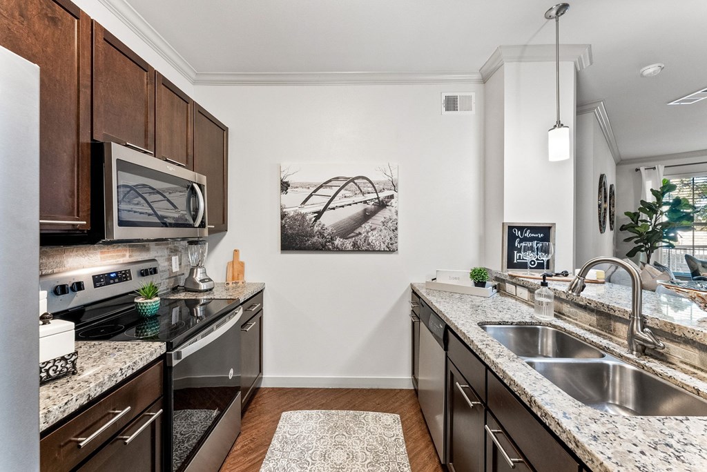 A kitchen with a black granite countertop and a white sink. at Bridge at Indigo, Austin, TX, 78717