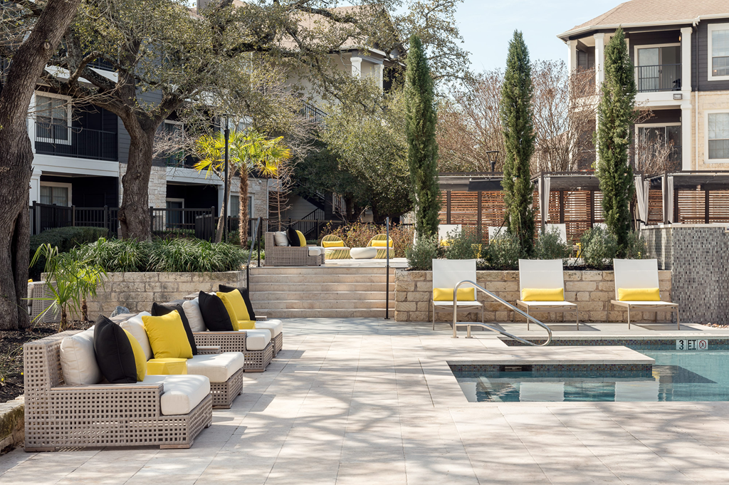 a patio with chairs and a pool in a courtyard