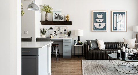 a living room with a couch and a desk and a kitchen