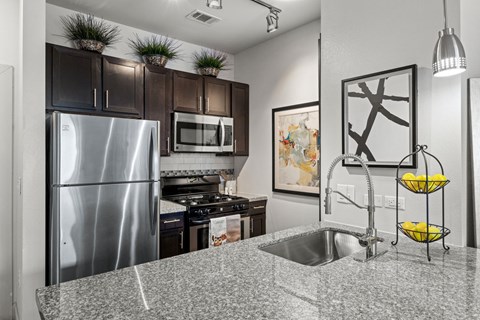 A kitchen with a stainless steel refrigerator and a granite countertop.