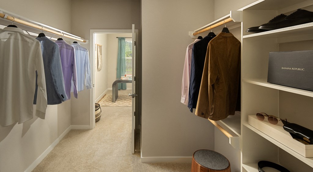 a walk in closet with racks of clothes and a door to a bathroom