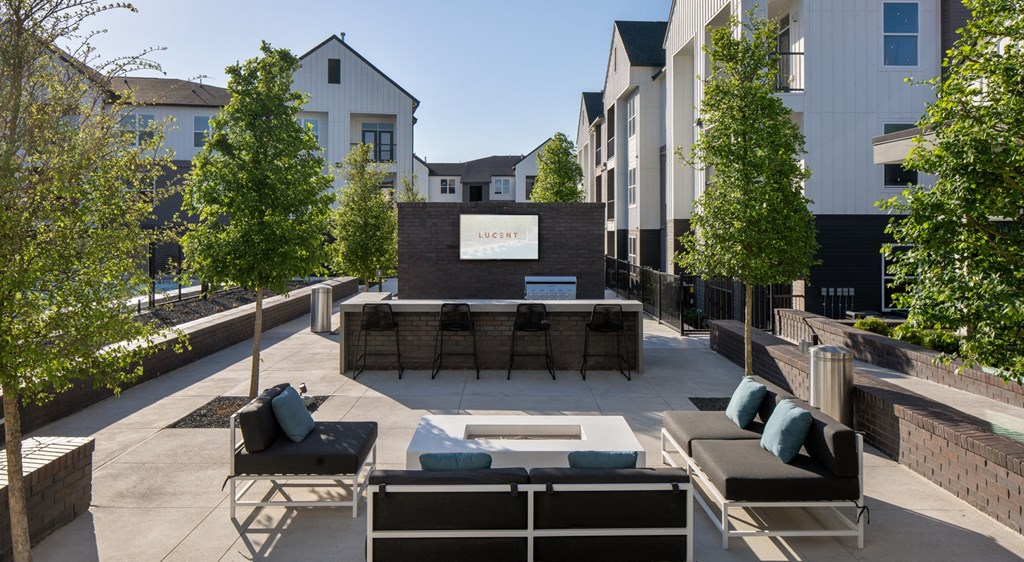 an outdoor patio with a fire pit and chairs and trees