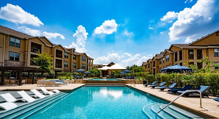 a swimming pool with lounge chairs and buildings in the background