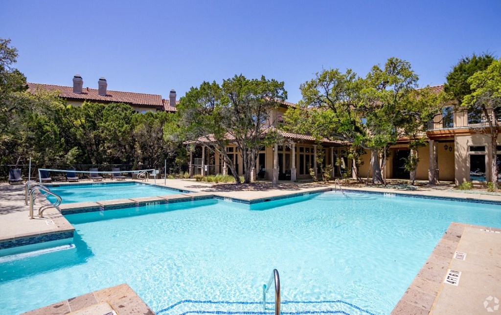 a swimming pool with two pools and a house in the background