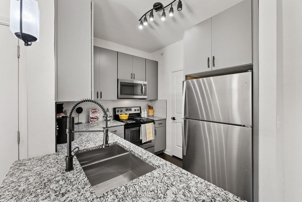 A kitchen with a stainless steel refrigerator and a sink with a black faucet. A kitchen with a stainless steel refrigerator and a sink with a black faucet. at Preserve at Rolling Oaks, Austin, TX