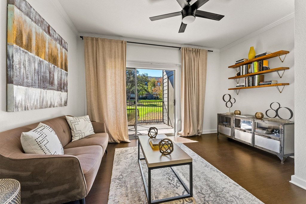 A living room with a brown couch, a coffee table, and a ceiling fan. at Preserve at Rolling Oaks, Austin, TX