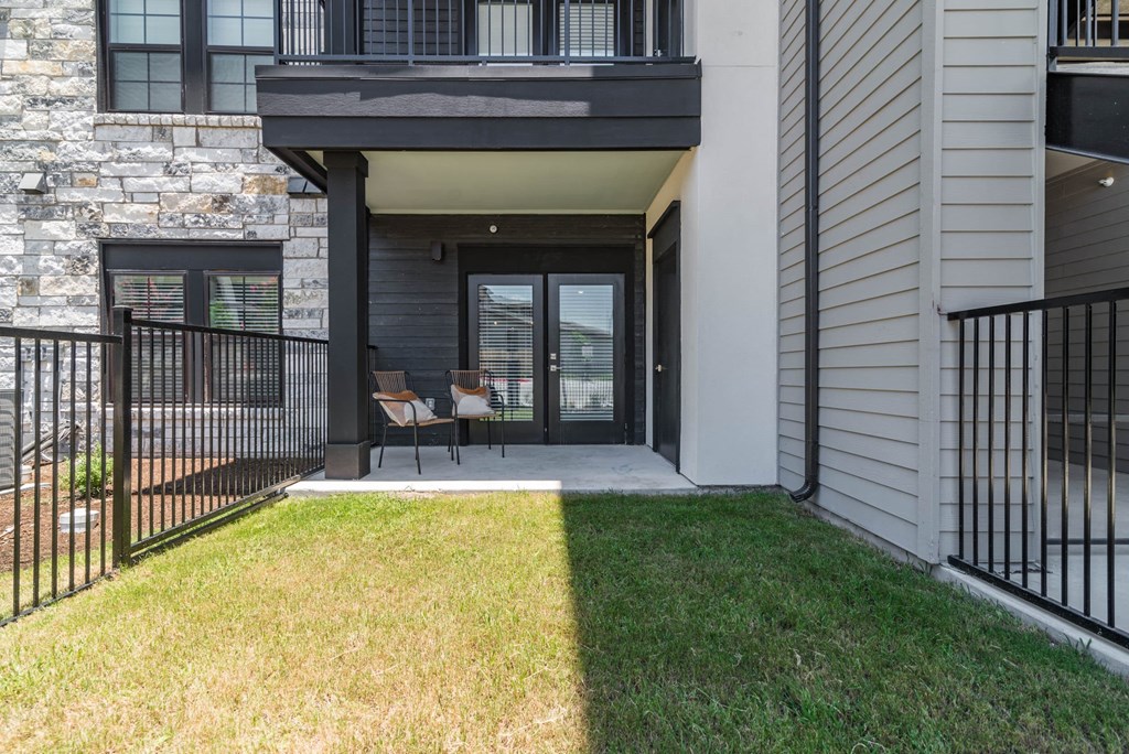 the yard of a building with a patio and chairs