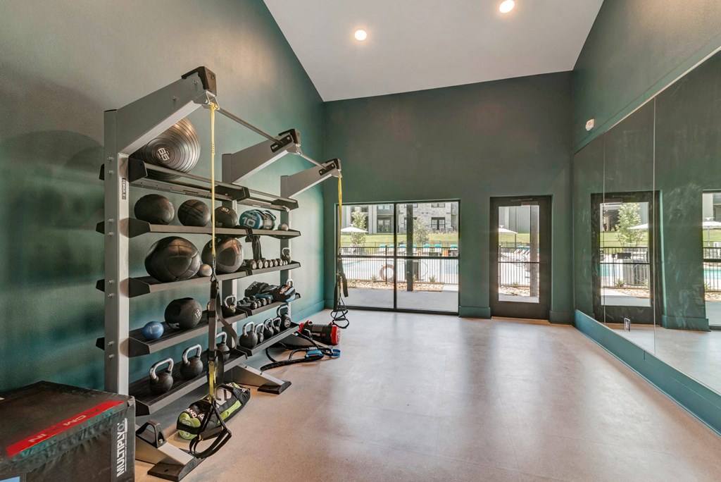the gym has a wall of glass doors and a large shelving unit with weights