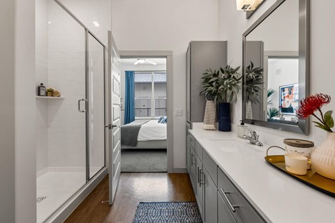 A bathroom with a walk-in shower and a double sink vanity. at The Haywood Apartments, Austin, 78748