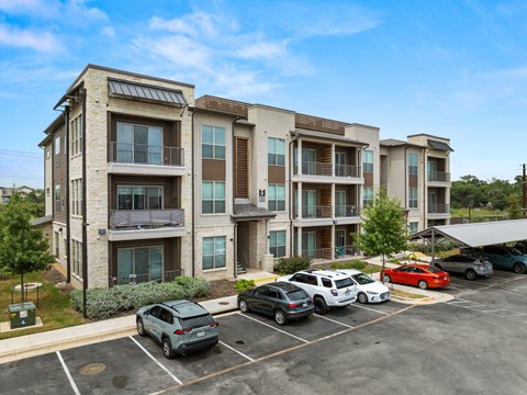 A parking lot with cars and apartment buildings in the background. at The Haywood Apartments, Austin