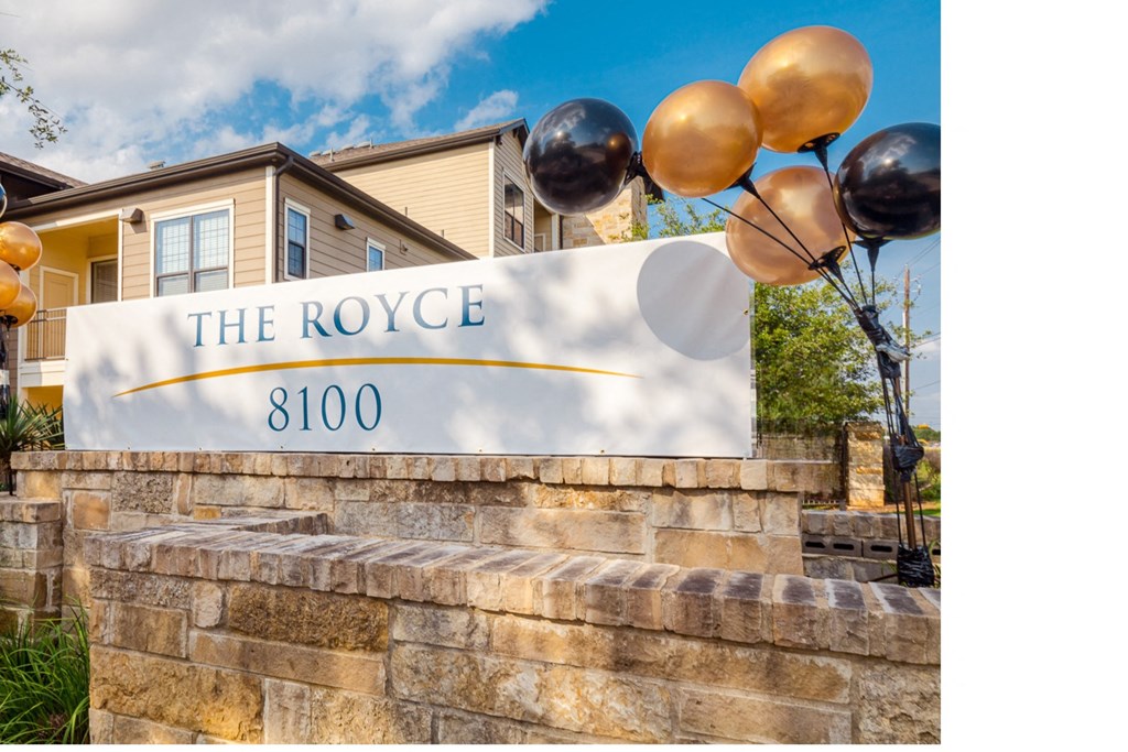 a stone retaining wall with a sign for the royce with balloons on it