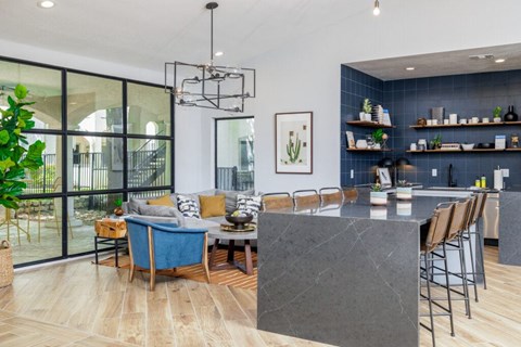 A modern kitchen with a large island and a dining area with a blue couch.