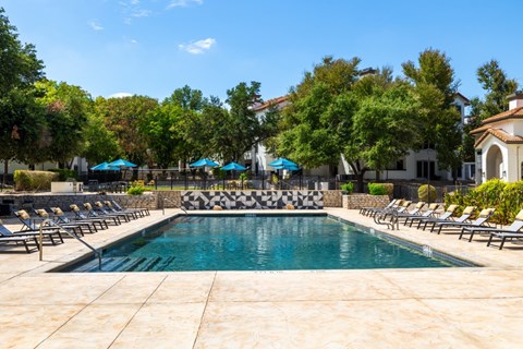 A pool surrounded by lounge chairs and umbrellas.