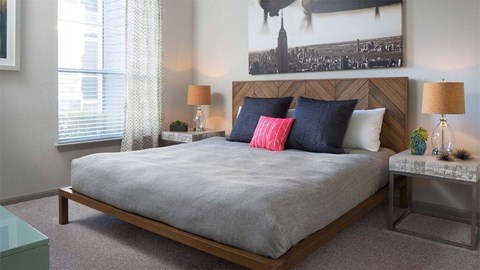 A bedroom with a large bed and a picture of a cityscape on the wall.
