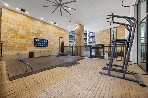 A gym with a treadmill, weights, and a television.