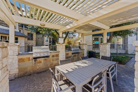 A patio with a table and chairs under a white pergola.