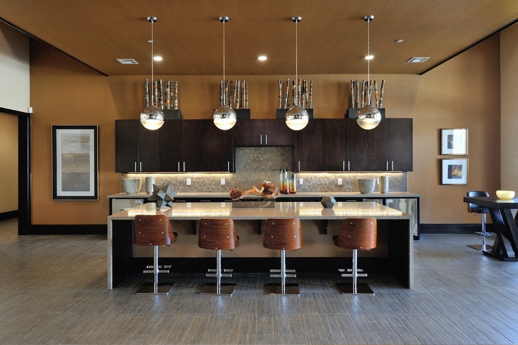 a modern kitchen with a large island and bar with chairs and lights