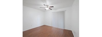 A room with a ceiling fan and wooden flooring.