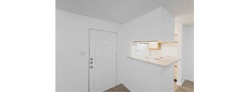 A white door is on the left and a white counter with a mirror above it is on the right.