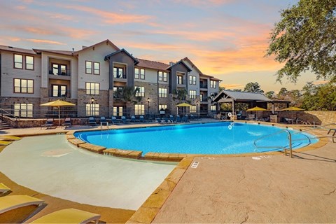 A large swimming pool is surrounded by a resort style building.