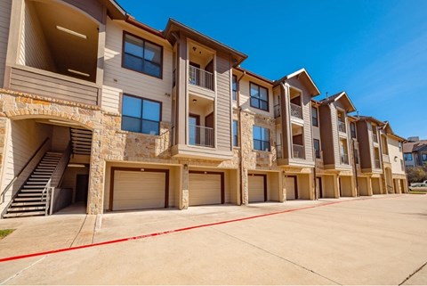 A row of modern apartment buildings with garages and balconies.