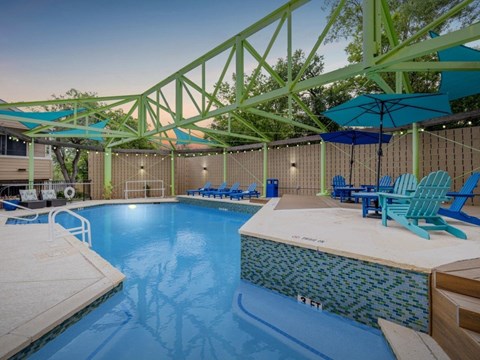 A large indoor swimming pool with a blue tiled edge and a white diving board.