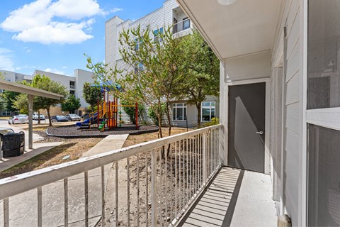 A balcony with a metal railing overlooks a playground.