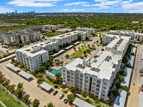 A large apartment complex with a swimming pool and a view of the city skyline.
