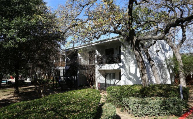a white house with trees and bushes in front of it