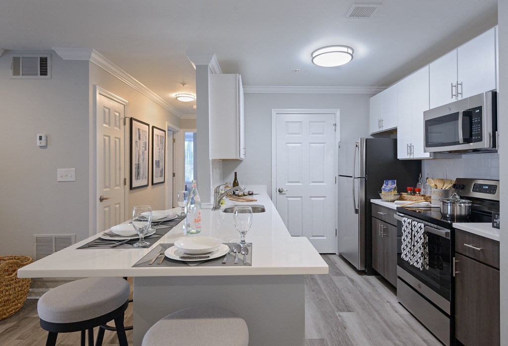 a kitchen with a large island with a white counter top and a black stove top oven