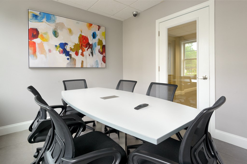 a meeting room with a white table and black chairs