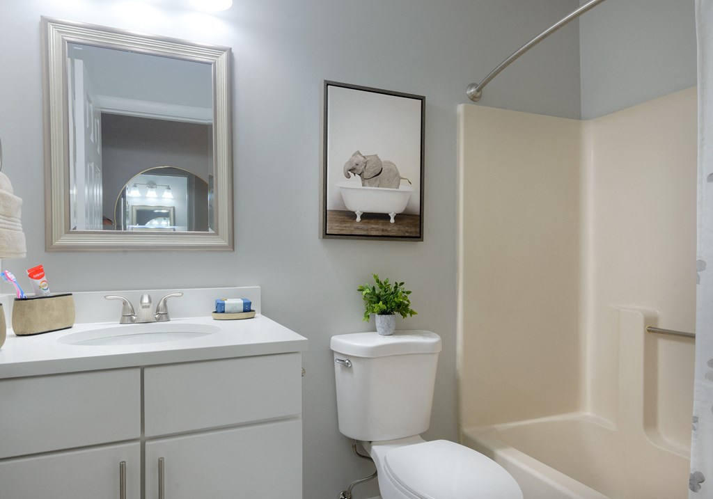 a small bathroom with a white vanity and toilet next to a white bathtub with a shower
