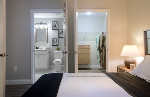 a bedroom with a large bed and a bathroom in the background