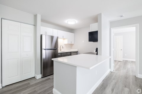 A modern kitchen with white cabinets and a stainless steel refrigerator.