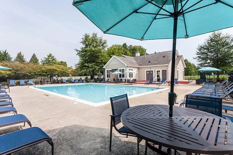 A blue umbrella is on a table next to a pool.