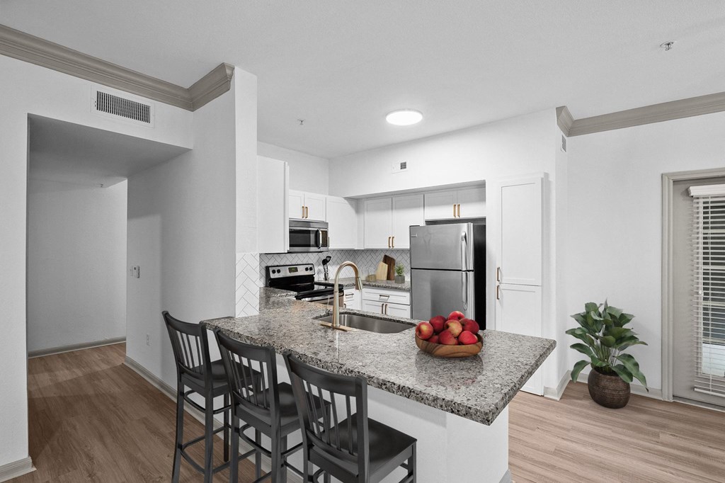 white kitchen with island and barstools and stainless steel appliances at The Aster Sugar Land, Sugar Land, TX