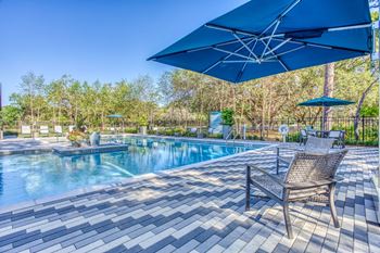 a swimming pool with chairs and umbrellas next to it at The Beck at Hidden River, Florida , 33637