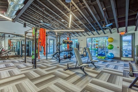a gym with weights and cardio equipment and a large window