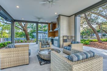 a covered patio with wicker furniture and a fire pit at The Beck at Hidden River, Florida , 33637