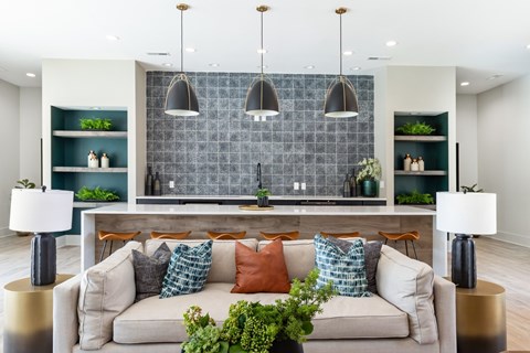 A modern living room with a grey couch and a grey tiled backsplash.