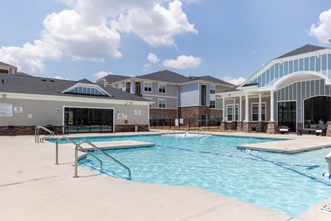 A swimming pool in front of a building with a glass wall.
