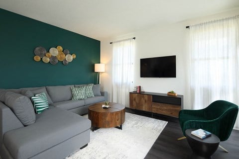a living room with a green accent wall and a gray couch