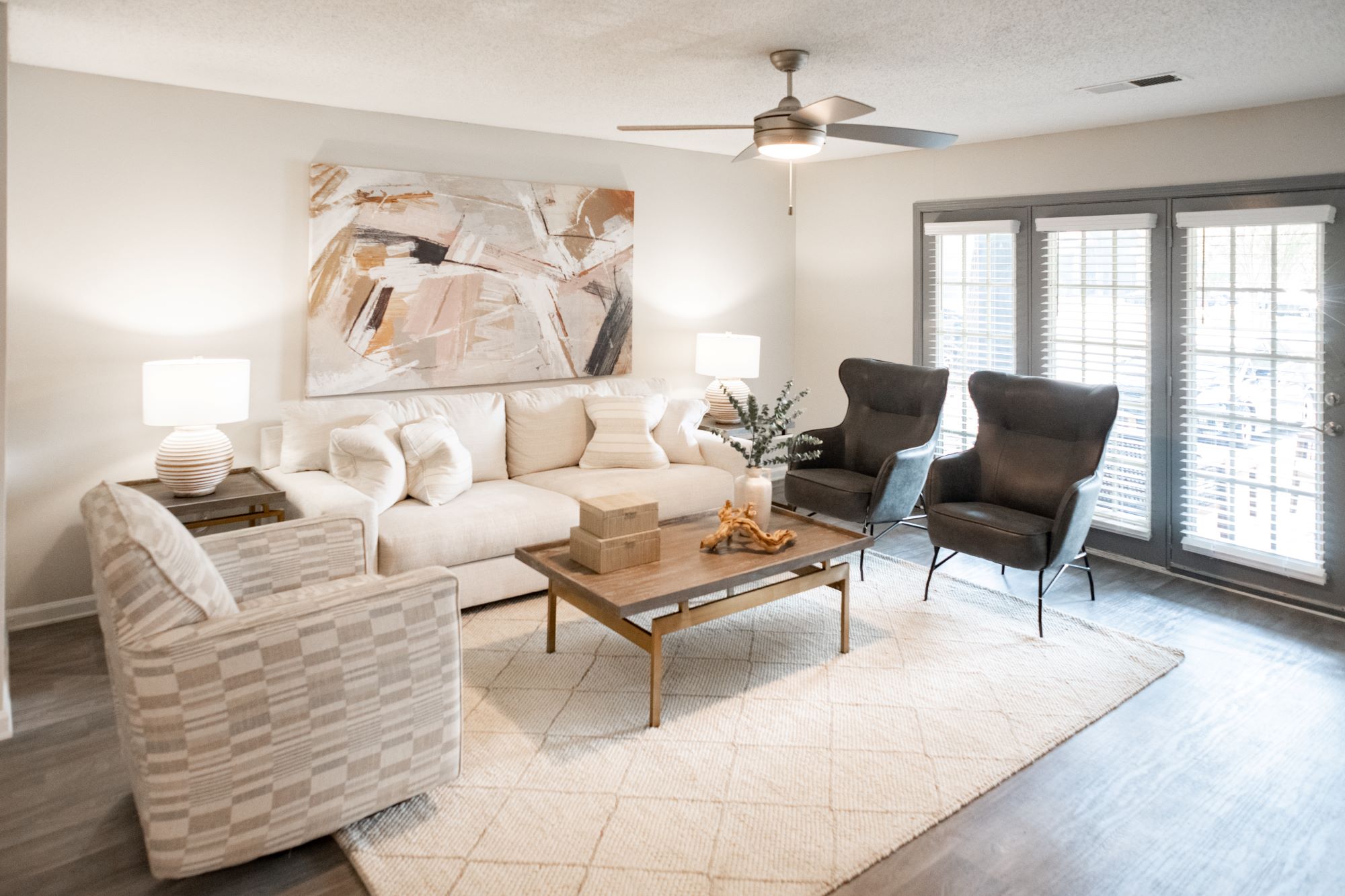 A living room with a white couch, a chair, and a table with a vase on it.