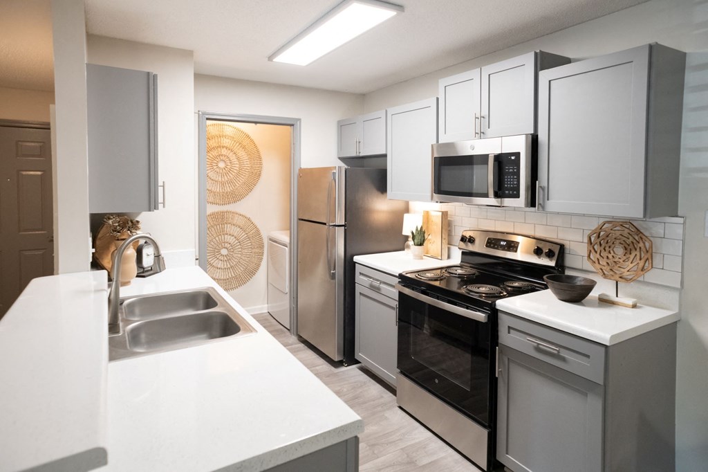 A modern kitchen with stainless steel appliances and white countertops. at The Addison at Collierville, Tennessee