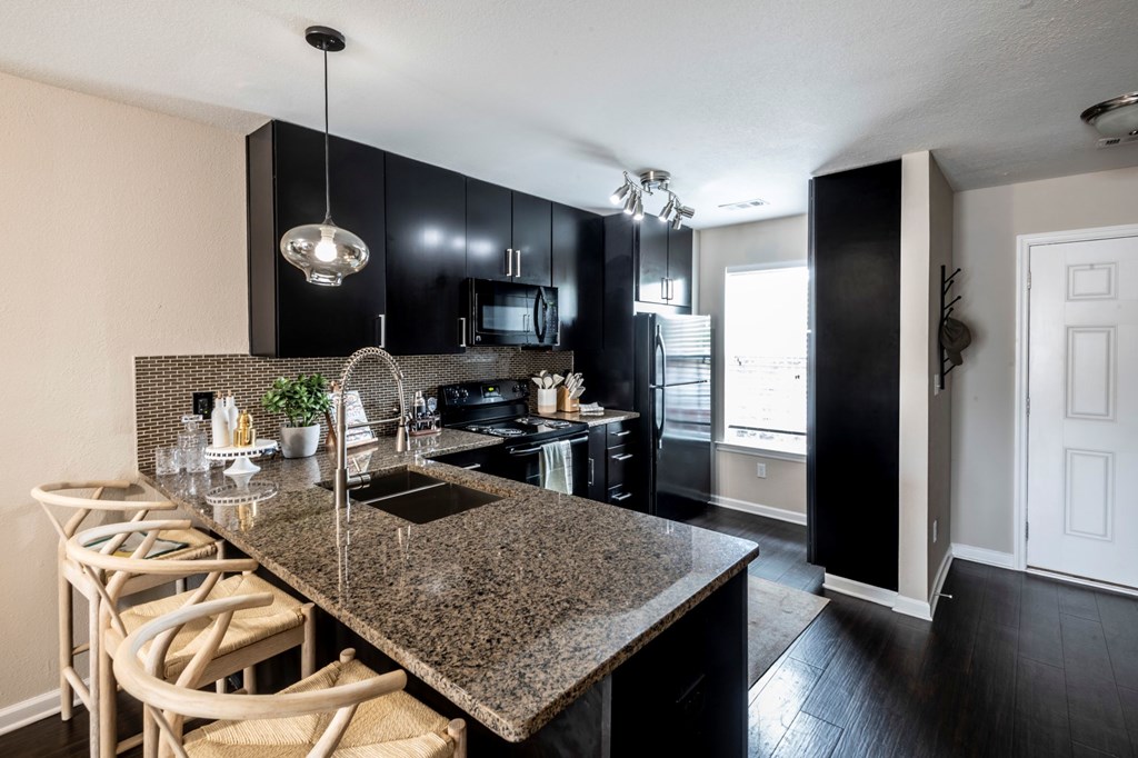 A kitchen with black cabinets and granite countertops.