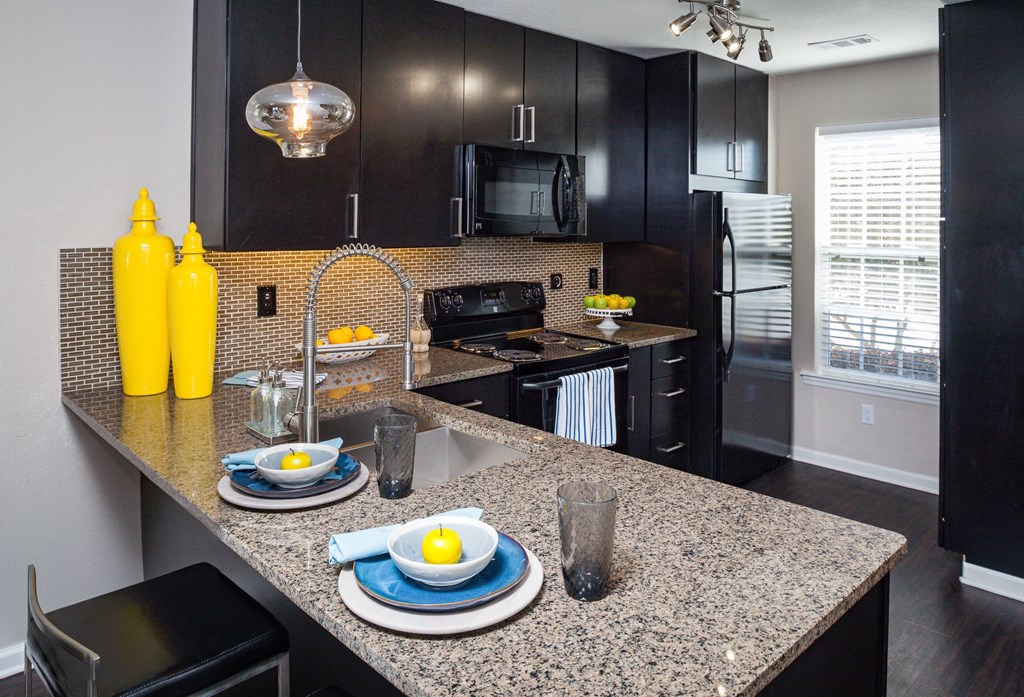 a kitchen with black cabinets and a granite counter top