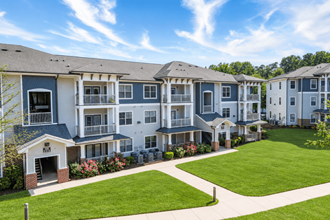 A row of townhouses with a green lawn in front.