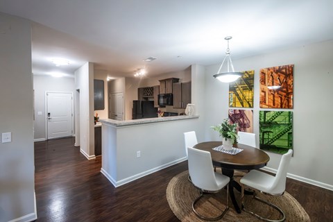 A dining room with a table set for two and a kitchen area in the background.