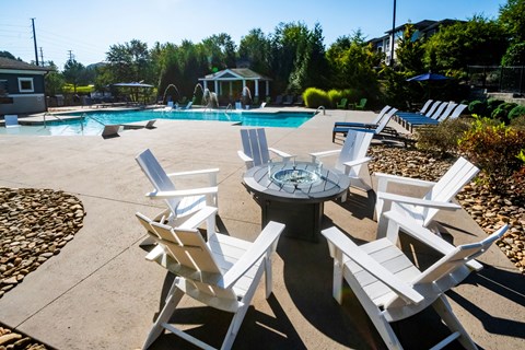 A poolside area with white chairs and a table.