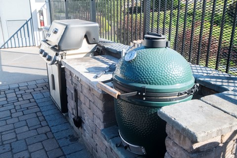 A green grill is on a stone platform.
